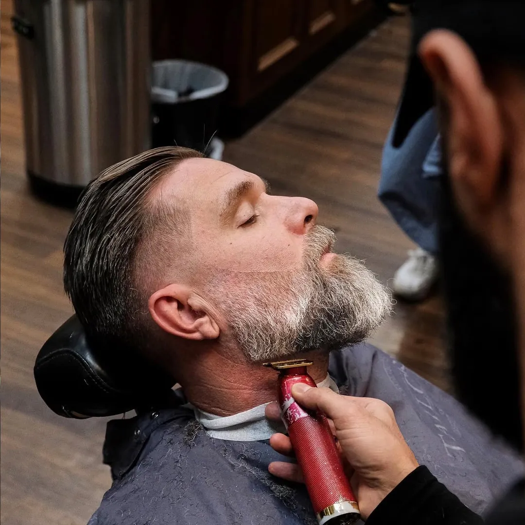 Barberare som trimmar halslinjen med trimmer