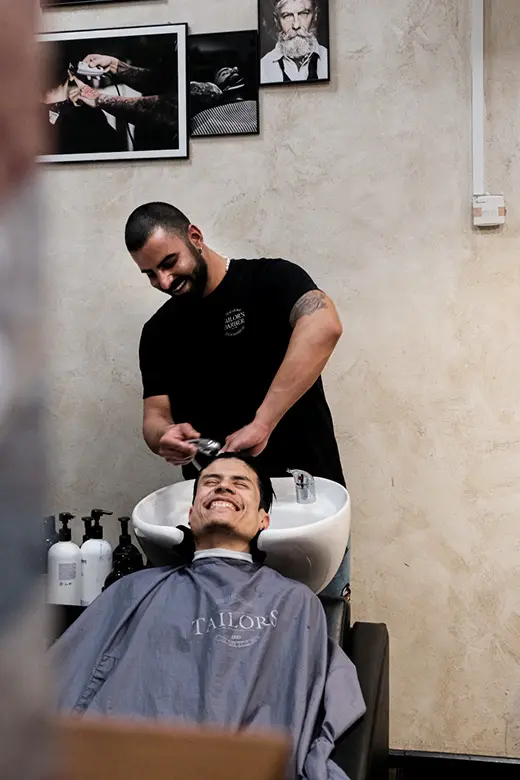 Barberare tvättar kundens hår på Tailor’s Barber i Stockholm inför herrklippning.