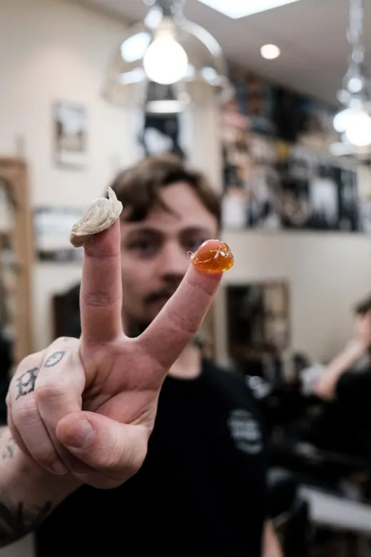 Barberare visar stylingprodukter för herrfrisyr på Tailor’s Barber i Stockholm.
