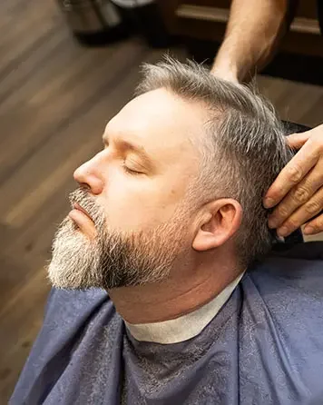 Barberare trimmar och stylar skägg på kund hos Tailor’s Barber i Åhléns City Stockholm