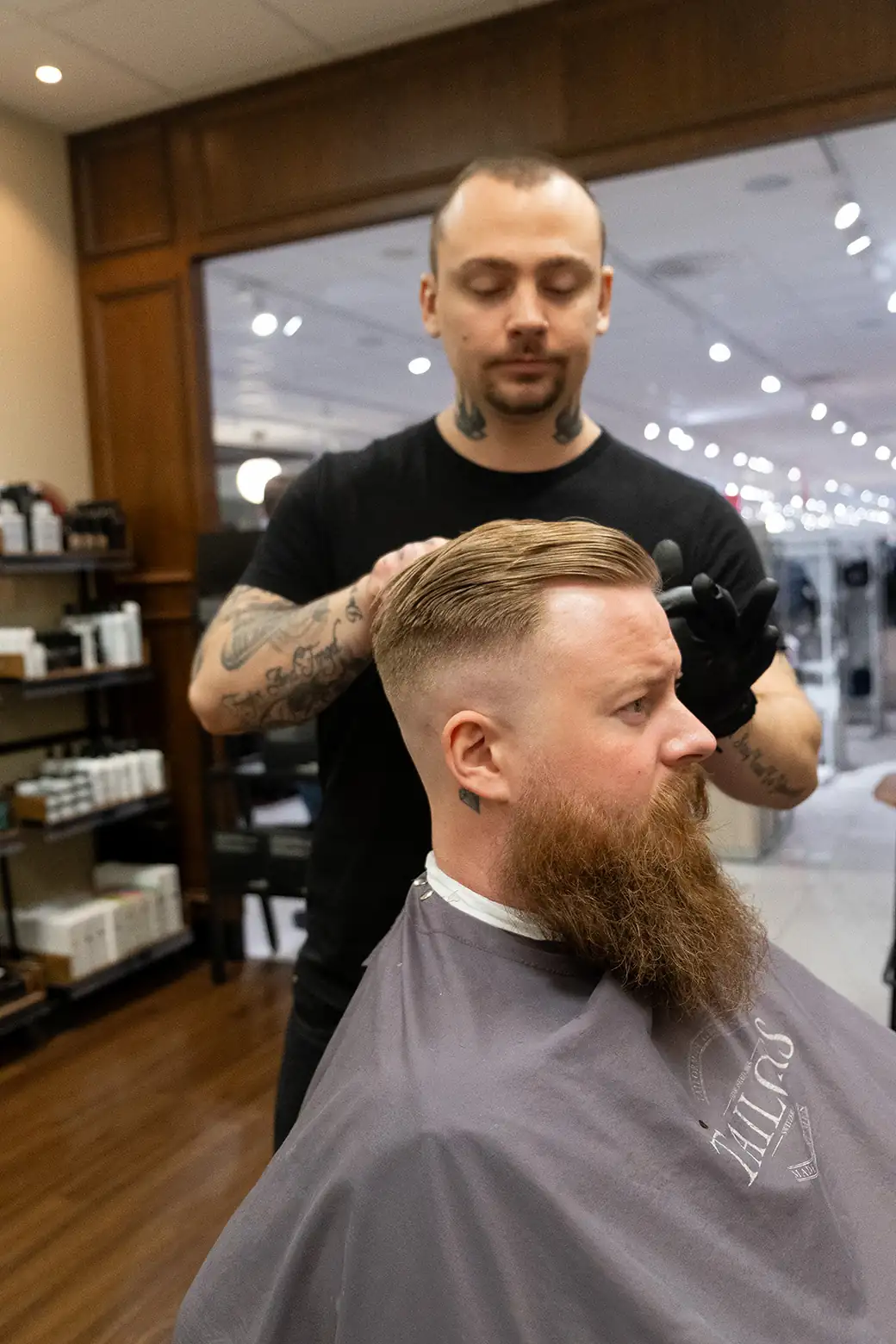 Kund får hårklippning och skäggtrimning av barberare på Tailor’s Barber i Stockholm City.