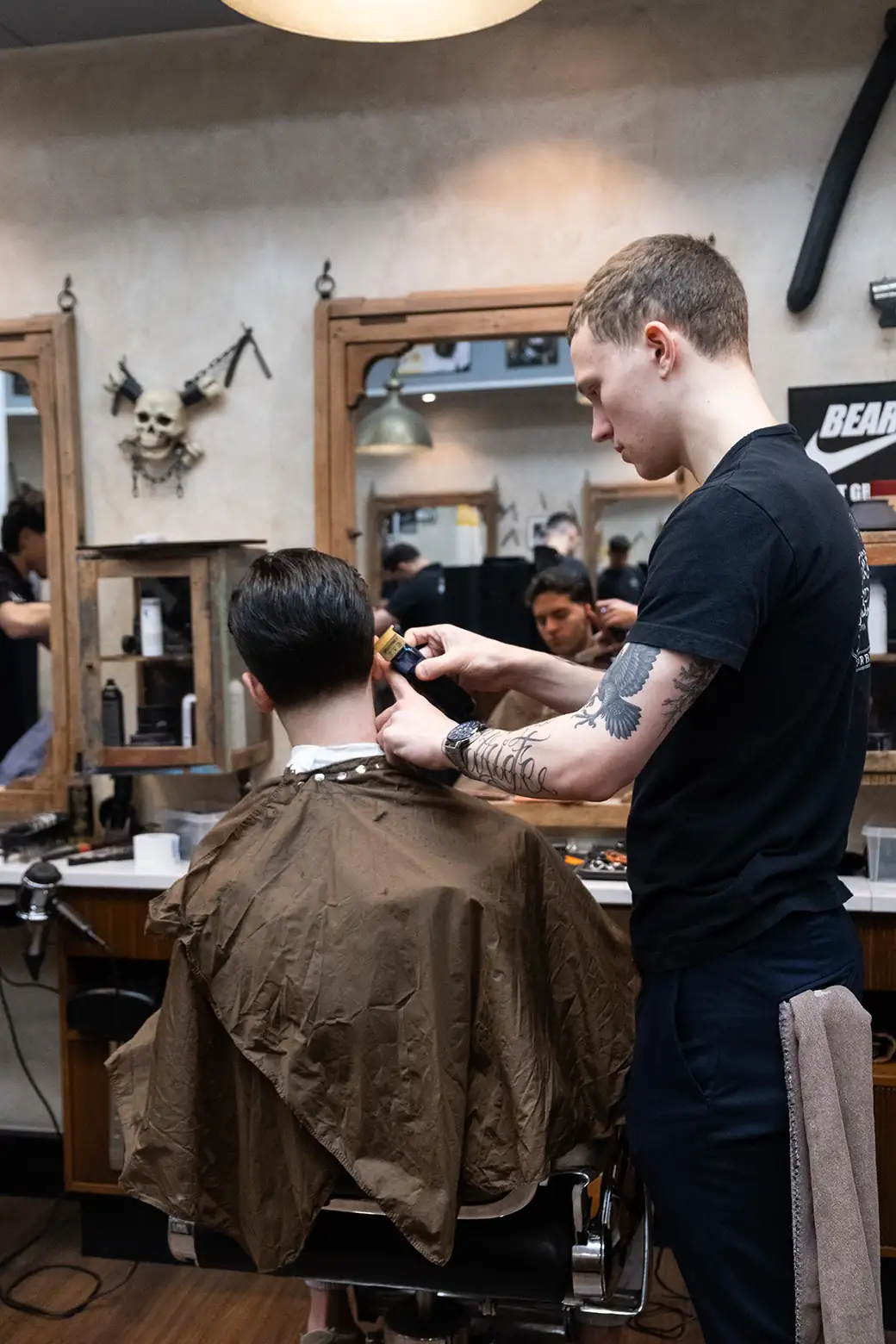 Barberare utför en taper fade på kund på Tailor’s Barber i Stockholm City.
