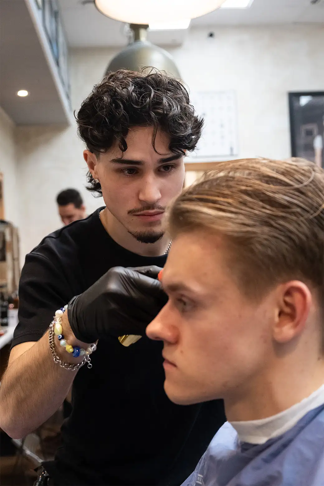 Barberare klipper kund på Tailor’s Barber i Stockholm City med fokus och precision.