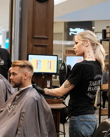 Barberare klipper en manlig kund på Tailor’s Barber med behandlingen herrklippning och skäggtrimning