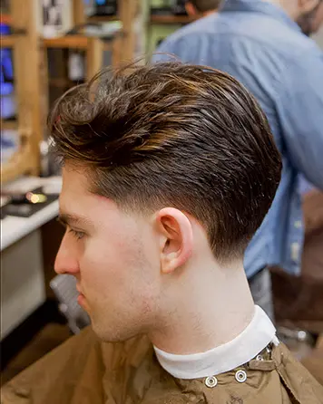 Taper fade från sidan på kund med korta sidor och längre hår upptill