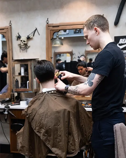 barber stockholm klipper sin kund med maskin vid örat.