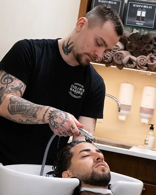 Kund som får sitt hår tvättat av barberare i stockholm